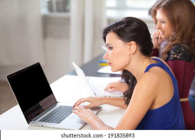 college students sitting in a classroom and using laptop computers