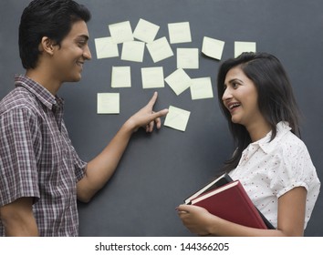 College Students Smiling In Front Of A Bulletin Board