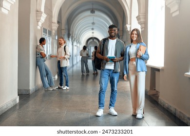 College students are socializing and studying in a university hallway with books and tablets, preparing for classes. They engage in academic discussions, teamwork, and a friendly atmosphere on campus - Powered by Shutterstock