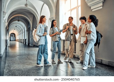 College students stand and talk in the university building. Multiethnic young people stand near classes, diverse college friends spending time indoors after lessons.                             - Powered by Shutterstock