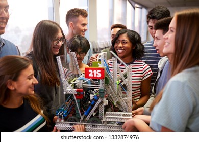 College Students With Teacher Holding Machine In Science Or Robotics Class