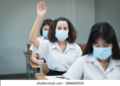 College students wear face mask study in classroom and raise hand to ask teacher during coronavirus pandemic. Selective focus portrait of university students study in the classroom. - Powered by Shutterstock