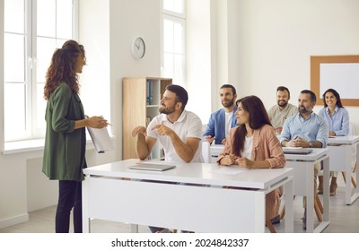 College teacher having class with group of interested adult male and female business course students. People sitting at tables in classroom, discussing topic of success, asking or answering questions - Shutterstock ID 2024842337