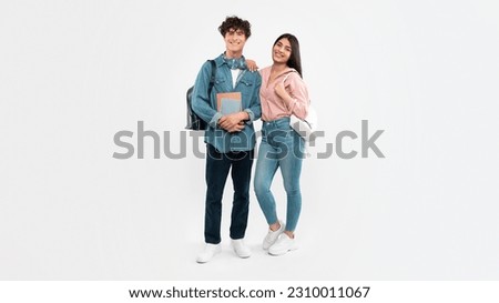 College Years. Full Length Shot Of Students Boyfriend And Girlfriend Posing Holding Textbooks And Backpacks On White Studio Background. Couple Of College Friends Smiling To Camera. Panorama