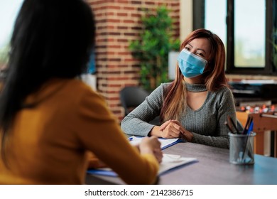 Collegues Discussing Marketing Strategy Analyzing Company Graphs Working At Business Partnership In Startup Office. Businesswomen Wearing Medical Face Mask To Prevent Infection With Covid19