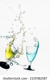 A collision of two glasses with colorful liquids with water splash from glass on a white background