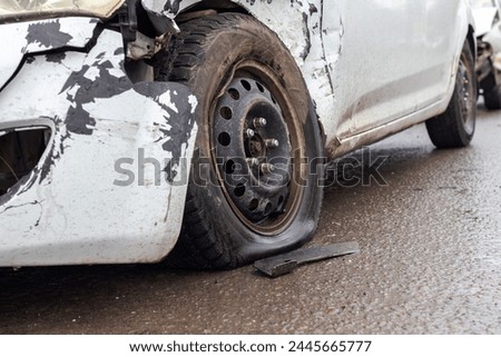 Collision of two white cars. Emphasis on the photo on the flat tire of one of the cars