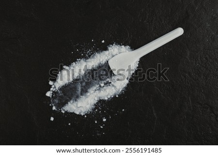 Colloidal silicon dioxide and plastic spatula on dark stone surface. Food additive E551. Enterosorbent. Silicon dioxide powder or Silica is used in medicine and food industry.