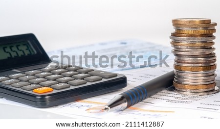 Collumn of coins on background of bills and checks, calculator and pen. Financical and banking concept, home finances