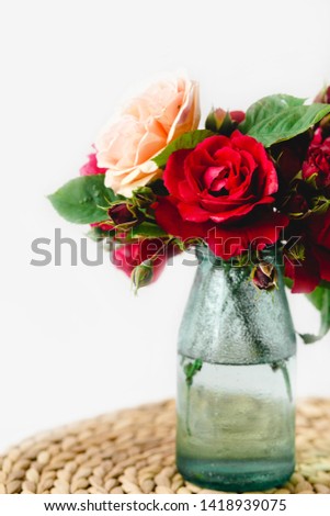 Coloful roses in vase on a wicker napkin on white background