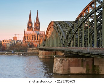 Cologne Cathedral In The Rays Of The Rising Sun And The Hohenzollern Bridge Over The River Rhine In The German City. Skyline Cologne.