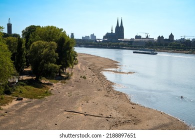 Cologne, Germany 10.08.2022: High Angle View Of Dried Up Rhine Riverbanks With The River At Historically Low Level Due To Heat Wave, Cologne Cathedral In The Background, One Kayaker On The Water