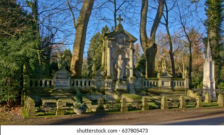 COLOGNE, GERMANY, 29 DECEMBER 2016,Old Family Grave Monument Wit Statues Of Jesus And Angels In Melaten Cemetery In A Green Environment On A Sunny Winter Day. Cologne, 29 December 2016