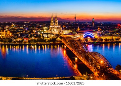 Köln, Deutschland: Schöne Panorama-Nachtlandschaft des gotischen Kölner Doms, der Hohenzollernbrücke und des Rheins bei Sonnenuntergang, goldener Stunde und blauer Stunde.