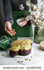 Colomba di Pasqua in the woman shef hands, traditional italian easter dove cake with green pistachio glaze,  fresh spring flowers, pasqua cake