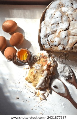 Colomba Pascal . Rustic table, raisins, eggs, slice of easter cake,  wooden spoon with sugar and flour in the composition.  Easter food, concept.
