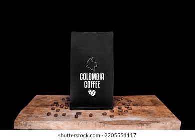 Colombia Coffee Beans And Black Package On Wooden Board With Black Isolated Background                  