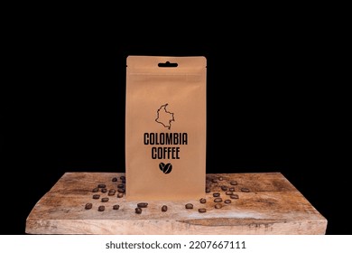 Colombia Coffee Beans And Eco Friendly Kraft Paper Package On Wooden Board With Black Isolated Background.