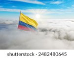 Colombia flag aerial view in beautiful sky with clouds. Top-down drone shot at sunrise or sunset. Aerial bird