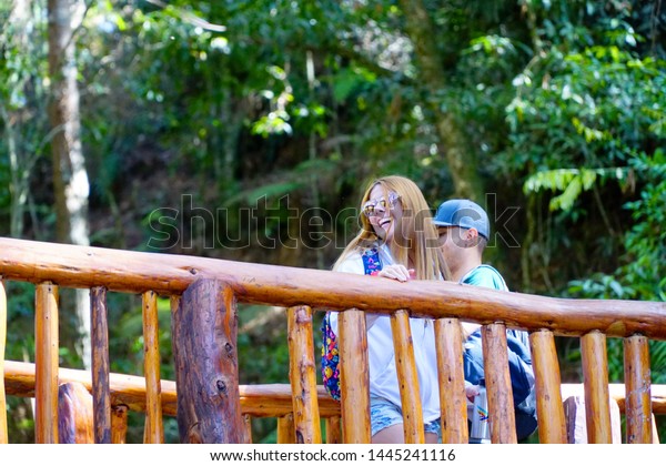 Medellín, Colombia; July 07 2019: People\
enjoy a healthy trip in the public park Arvi in the city of\
Medellin, with a lot of trees, wood bridge and a\
river