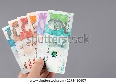 Colombian money - Pesos in the hand on a gray background 