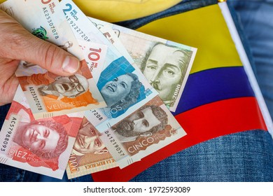 Colombian money, pesos, held in the hand together with the national flag. Economics concept 