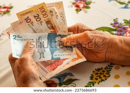 Colombian peso, a pensioner holds several banknotes in her hand, Financial problems of seniors, inflation and poverty in Colombia


