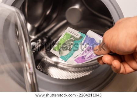 Colombian pesos being thrown into the washing machine, Concept, Money laundering, illegal activity, black market, Criminal activity in Colombia