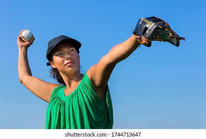 Colombian Woman With Baseball Glove And Cap Throwing Baseball In Blue Sky