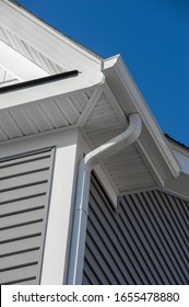 Colonial white gutter guard system,  soffit providing ventilation to the attic, with gray vinyl horizontal siding at a luxury American single family home neighborhood USA