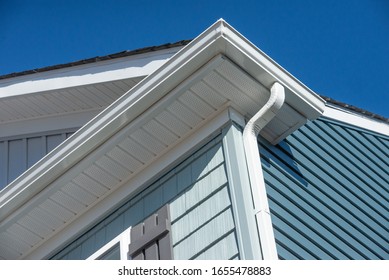 Colonial white gutter guard system, fascia, drip edge, soffit providing ventilation to the attic, with pacific blue vinyl horizontal siding at a luxury American single family home neighborhood USA