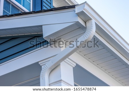 Colonial white gutter guard system, fascia, drip edge, soffit providing ventilation to the attic, with pacific blue vinyl horizontal siding at a luxury American single family home neighborhood USA
