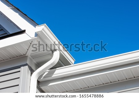 Colonial white gutter guard system,  soffit providing ventilation to the attic, with gray vinyl horizontal siding at a luxury American single family home neighborhood USA