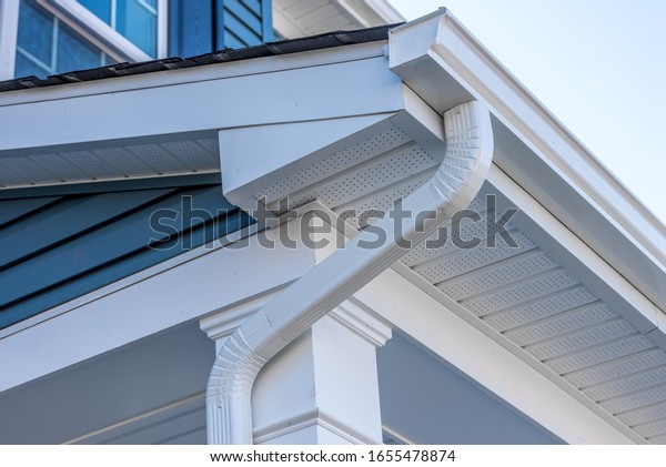 Colonial white gutter guard system, fascia, drip
edge, soffit providing ventilation to the attic, with pacific blue
vinyl horizontal siding at a luxury American single family home
neighborhood USA
