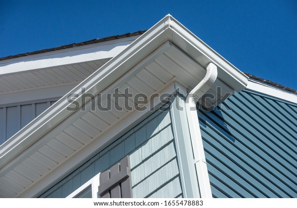 Colonial white gutter guard system, fascia, drip\
edge, soffit providing ventilation to the attic, with pacific blue\
vinyl horizontal siding at a luxury American single family home\
neighborhood USA