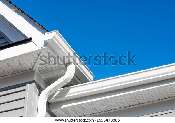 Colonial white gutter\
guard system,  soffit providing ventilation to the attic, with gray\
vinyl horizontal siding at a luxury American single family home\
neighborhood USA
