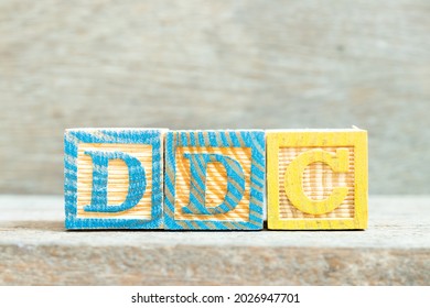 Color alphabet letter block in word DDC (Abbreviation of Division of disease control, Direct digital control, Display Data Channel or Dewey Decimal Classification) on wood background