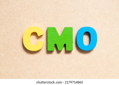 Color Alphabet Letter In Word CMO (Abbreviation Of Chief Marketing Officer, Contract Manufacturing Organization) On Wood Background