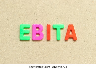 Color alphabet letter with word EBITA (abbreviation of  earnings before interest, taxes and amortization) on wood background