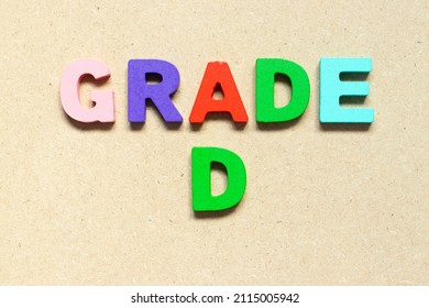Color alphabet letter with word grade D on wood background