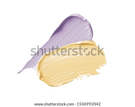 Color corrector strokes isolated on white background. Yellow and lilac color correcting concealer cream smudge smear swatch sample. Makeup cosmetic creamy texture