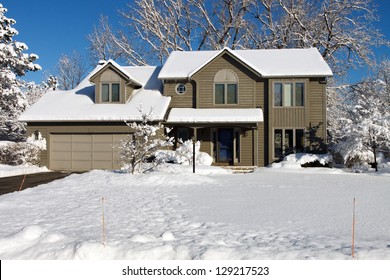 Color DSLR Picture Of A Suburban Colonial House Covered In White Winter Snow.  The Image Of The Home Is In Horizontal Orientation With Ample Copy Space For Text.