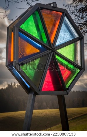 Color glass oval near green meadow and forest in Austria winter countryside