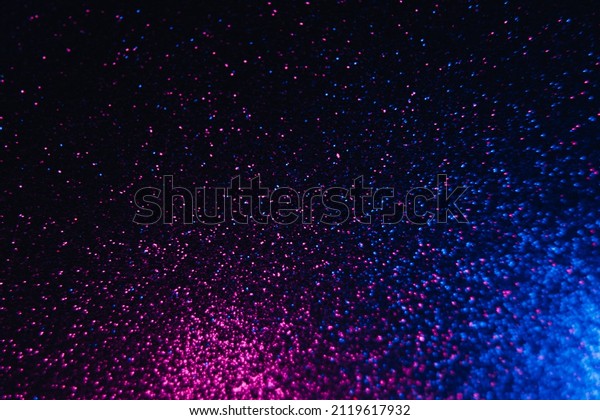 Color glitter overlay.\
Blur sparkles. Bokeh light. Night sky stars reflection. Neon blue\
magenta pink grain texture glow on dark black shimmering abstract\
background.