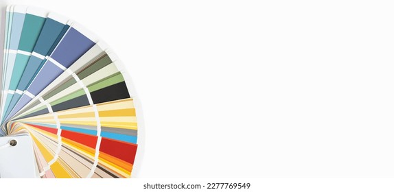 Color guide close up. Assortment of colors for design. Colors palette fan on a white concrete wall background. Graphic designer chooses colors from the color palette guide. Coloured swatches catalogue