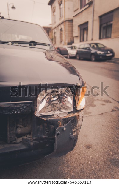 Color image\
of a crashed car with broken\
headlight.