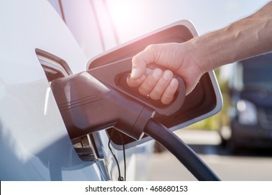 Color image of a man's hand preparing to charge an electric car. - Shutterstock ID 468680153