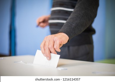 Farbbild einer Person, die während der Wahlen an einem Wahllokal eine Stimme abgibt.