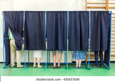 Farbbild einiger Wähler in einigen Wahlkabinen eines Wahlsenders.