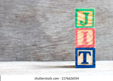 Color letter block in word JIT (abbreviation of just in time) on wood background